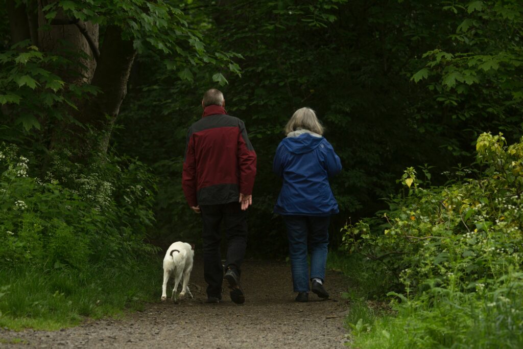 couple with a dog walking in the woods