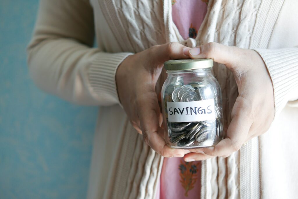 woman holding a jar of coins with tape that says savings on it